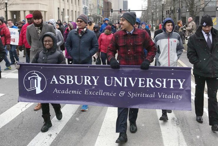 students carrying an Asbury University banner in a march