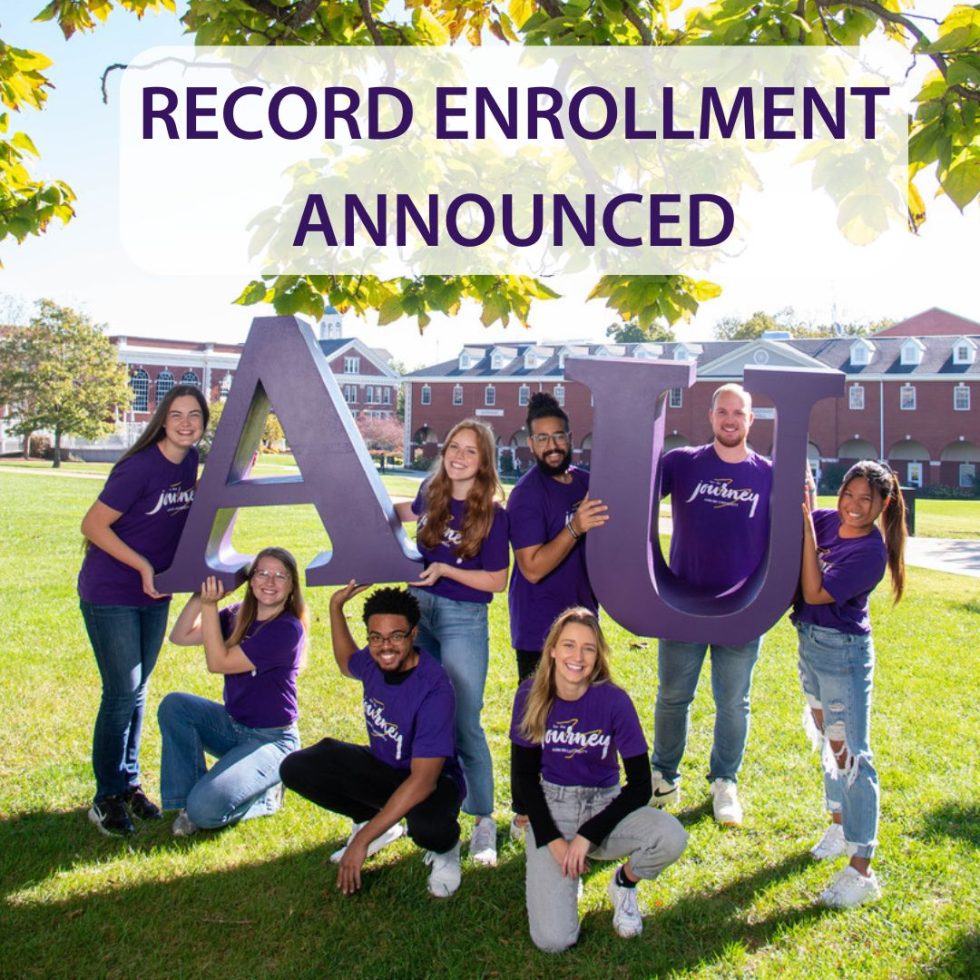 students smiling and holding the letters A and U on the Asbury University green lawn