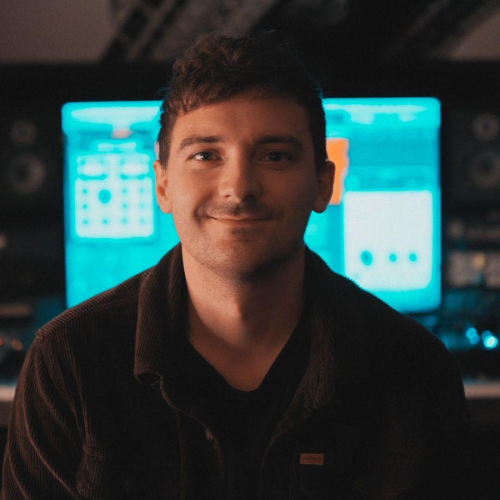 A man smiling in front of an audio editing computer screen